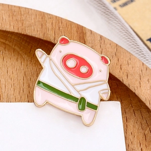 Cute pink pig enamel pin wearing white karate uniform with green belt on white card