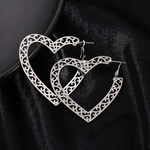 Bohemian silver hollow heart earrings with vintage filigree on black silk background