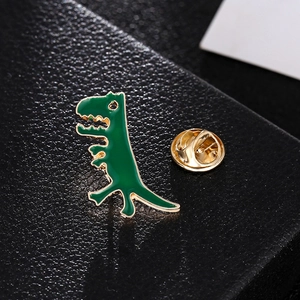 Cute dark green enamel dinosaur brooch with golden metal edges on black leather background