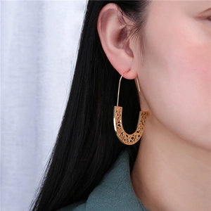 Elegant gold-tone U-shaped hollow earrings with geometric patterns on model