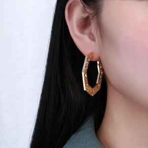 Bohemian gold hollow hexagon hoop earrings for women shown on a fashion model