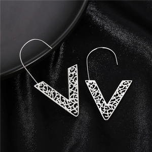 Fashion silver V-shaped hollow geometric earrings with vintage filigree on silk background