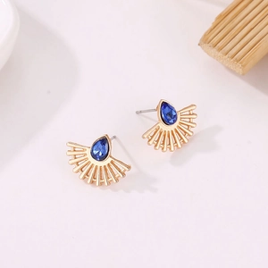 Detailed view of fan-shaped golden earrings featuring a blue teardrop stone
