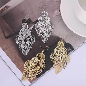 Détails de boucles d'oreilles feuilles évidées en or et argent sur une page de magazine