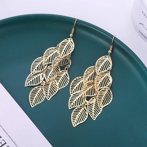 Détail de boucles d'oreilles feuilles dorées superposées avec veines évidées