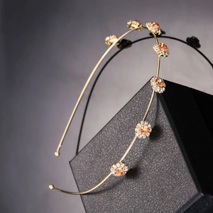 Detail of gold metal headband featuring amber and clear crystal flower clusters on gift box