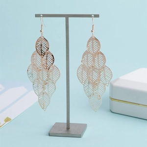 Détail des boucles d'oreilles feuilles évidées en or rose sur support de bijoux
