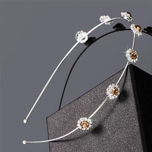 Silver metal floral headband with amber rhinestones on a textured black display