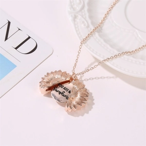 Collier médaillon tournesol en or rose avec gravure sur fond blanc élégant