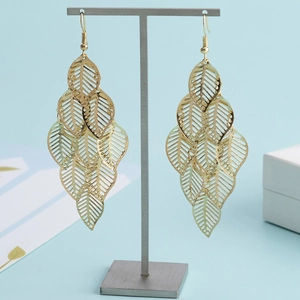 Boucles d'oreilles pendantes feuilles dorées ajourées sur un présentoir en forme de T