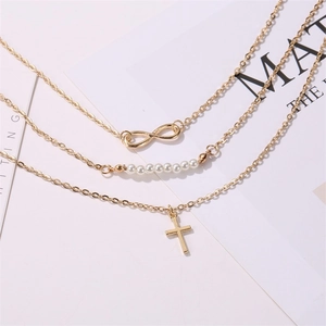 Collier doré à trois couches avec symbole infini, perles et pendentif croix sur fond blanc