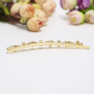 Vue détaillée d'une barrette dorée ornée de perles blanches et de petits cristaux