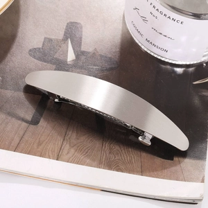 Barrette à cheveux ovale en métal argenté brossé au design minimaliste sur magazine