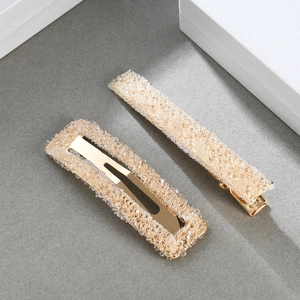 Close-up of golden hair clip set with sparkling champagne crystals on a gray surface