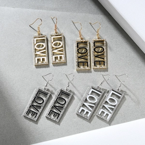 Detail von vier rechteckigen LOVE-Ohrhängern mit Kristallen in Gold- und Silberfarben