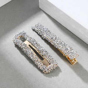 Close-up of a silver two-piece hair clip set with sparkling rhinestones on a textured base