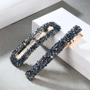 Detailed close-up of two vintage-style gold hairpins with navy blue rhinestones
