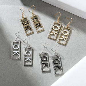 Detailansicht geometrischer Ohrringe in Gold und Silber mit OK-Buchstaben und Strass