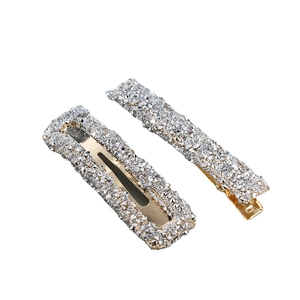 Two-piece set of gold alloy hair clips with silver rhinestones on a white background
