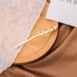Gros plan détaillé d'une barrette dorée LOVE sur un plateau en bois minimaliste