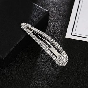 Detailed view of silver hair clips with sparkling rhinestones on black background