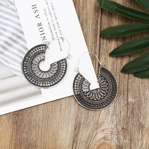 Vintage bohemian silver hollow hoop earrings displayed on a natural wood surface