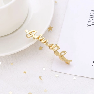 Détail d'une pince à cheveux dorée Amore sur tulle blanc et paillettes en étoiles