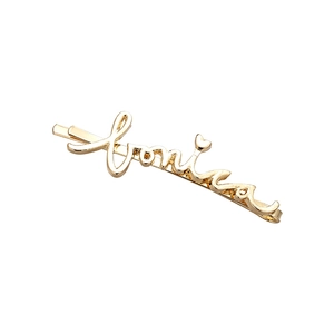 Gros plan sur la barrette dorée Lonia en écriture cursive avec un petit détail de cœur