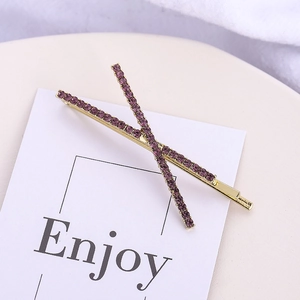 Detail shot of golden metal hair clips set with purple rhinestones on a card