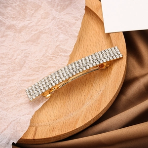 Detail view of a luxury gold metal hair clip with 4-5 rows of sparkling white rhinestones