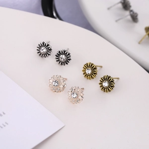 Detailed view of three pairs of sunflower stud earrings in silver, bronze and rose gold
