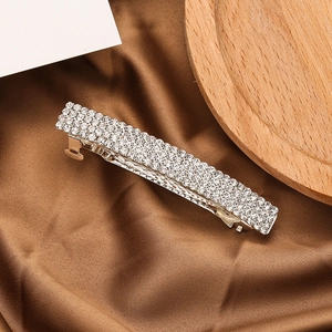 Close-up of sparkling rhinestone hair clip on elegant dark brown silk satin fabric