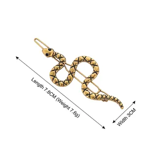 Golden snake-shaped hair clip with black scale texture and bead eyes on white background