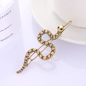 Minimalist golden snake hair clip with black scale details and sparkling gemstone eyes