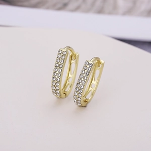 Vue macro de boucles d'oreilles ovales dorées en U avec double rangée de cristaux