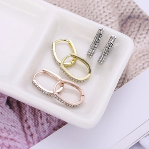 Lot de boucles d'oreilles U serties de cristaux en or rose et argent sur plateau blanc