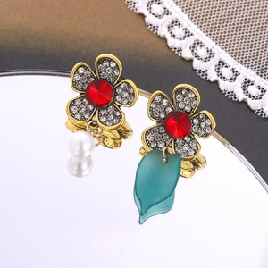 Detail view of vintage asymmetric flower earrings with pearls and emerald green leaves