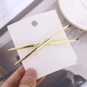 Minimalist gold polished cross metal hair clips for women on a white display card