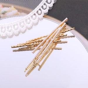 Elegantes goldenes Haarklammer-Set mit weißen Perlen und Wellenmuster auf einem Spiegel
