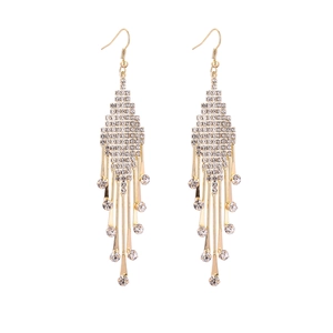 Détail de longues boucles d'oreilles dorées à pampilles et strass sur fond blanc