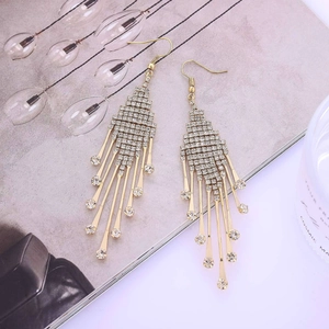 Gros plan de boucles d'oreilles dorées à longs glands avec strass étincelants sur magazine