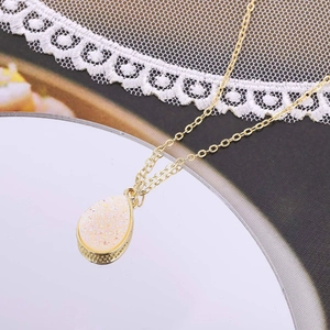 Détail du pendentif en forme de goutte d'eau avec texture cristal jaune et bord doré