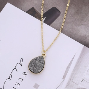Collier doré avec pendentif goutte d'eau et pierre druzy grise sur carte blanche