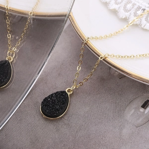 Détail d'un pendentif en cristal noir en forme de goutte d'eau avec une chaîne dorée