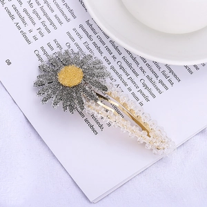 Détail de la pince à cheveux marguerite perlée avec cristaux gris et base dorée