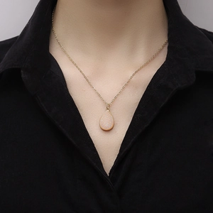 Élégant collier plaqué or avec pendentif goutte en druzy rose sur une chemise noire