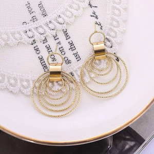 Elegant gold multi-layer textured hoop earrings displayed on white lace and ceramic