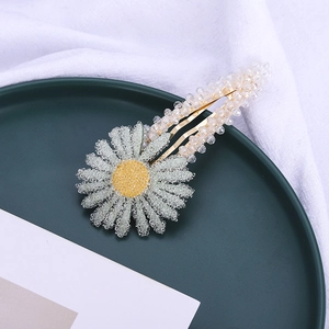 Détail d'une pince à cheveux marguerite avec perles claires et base en métal doré
