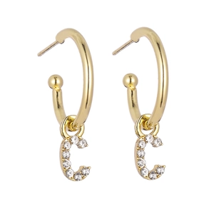 Detail of gold letter C hoop earrings with white rhinestones on a white background