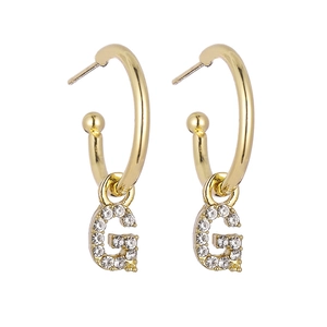 Detail of gold hoop earrings with sparkling crystal-encrusted letter G pendant charms